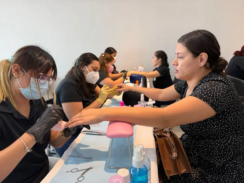 Fila de alumnas trabajando las uñas de sus modelos en clase