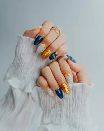 Uñas con diseño en azul marino, dorado y blanco