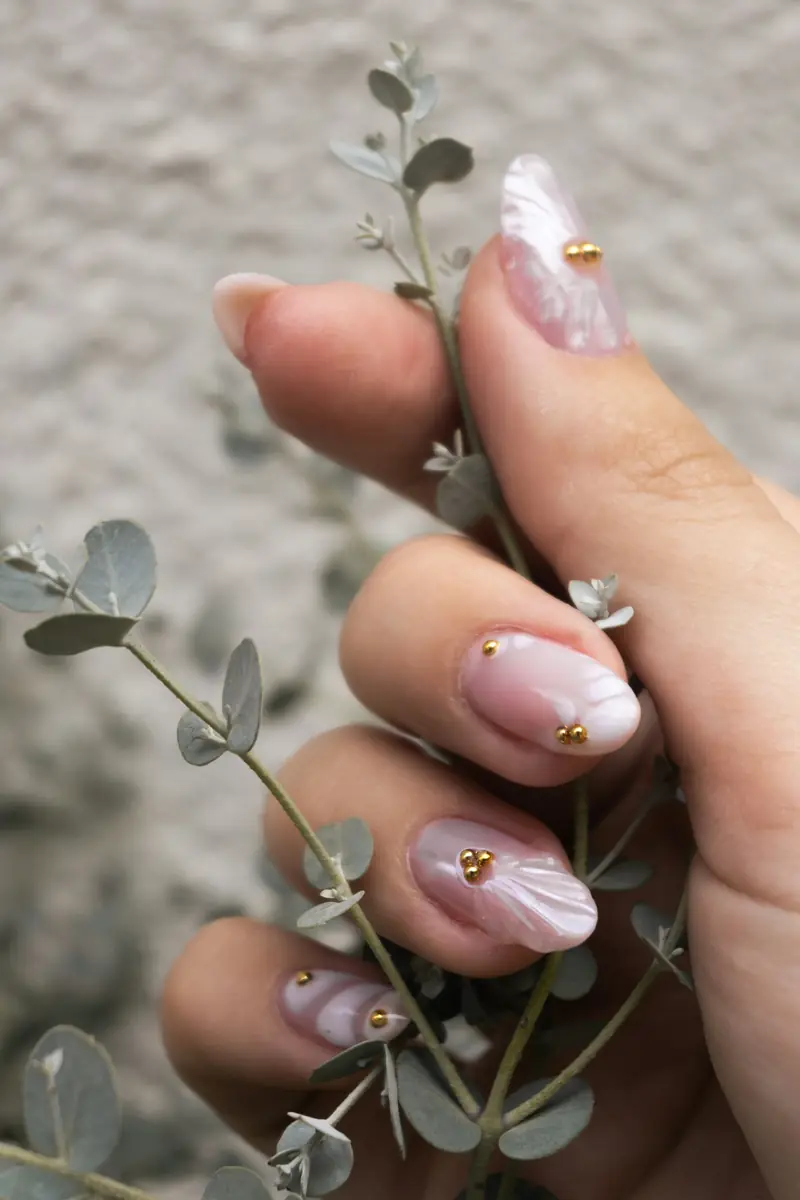 Uñas en tono rosa suave con detalles dorados y perla